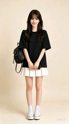 Woman with long dark hair wearing a black t-shirt and white pleated skirt
