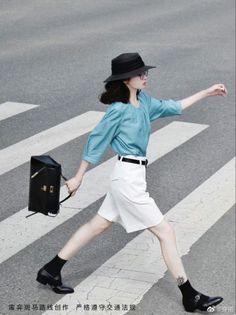Woman in a black hat and blue shirt crossing a street on a crosswalk
