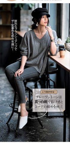 Woman in a black hat and gray outfit sitting at a cafe counter