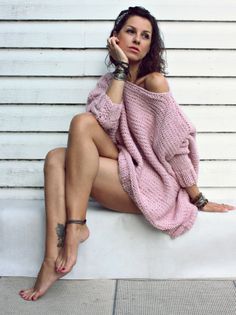 Woman in a pink off-shoulder sweater and headband, sitting barefoot