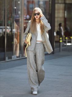 Woman in a striped suit, crop top, and sunglasses walking outdoors