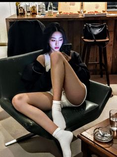 Woman in a white tank top and shorts sitting on a chair indoors