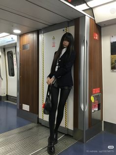 Woman in a school uniform and black tights standing in a subway train