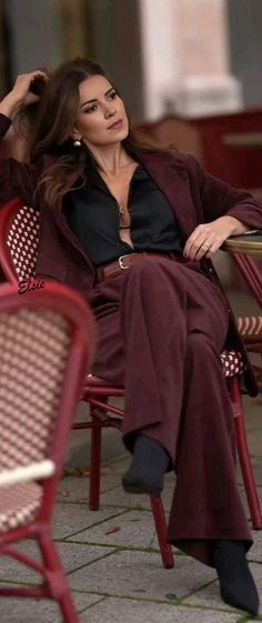 Woman in a burgundy suit and black shirt sitting outdoors