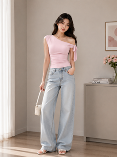 Woman in a pink one-shoulder top and wide-leg jeans holding a white handbag