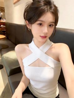 Woman in a white criss-cross top with an updo hairstyle indoors