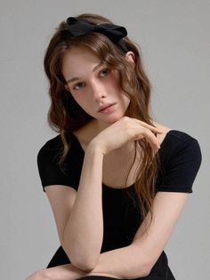 Woman with long wavy hair and a black headband in a studio setting