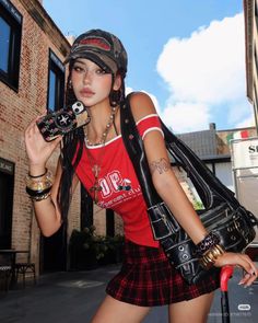 Woman in a red top and plaid skirt holding a phone and bag on a street
