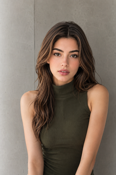 Woman with long dark brown hair wearing a green sleeveless top indoors