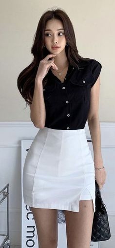 Woman with long hair wearing a black shirt and white mini skirt indoors