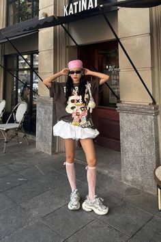 Woman in a pink bandana and oversized t-shirt with a white mini skirt on a street