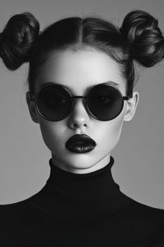 Woman with space buns, round sunglasses, and black lipstick in a turtleneck