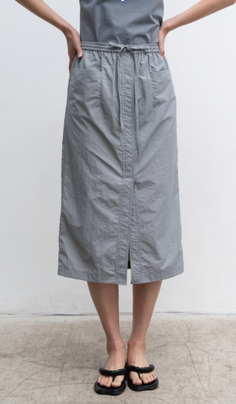 Person wearing a grey midi skirt with a drawstring waist and black sandals