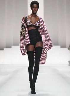 Runway model in a striped shirt, bra top, high waisted shorts, and thigh high stockings