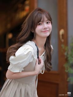 Woman with long brown hair wearing a dress with puffy sleeves outdoors