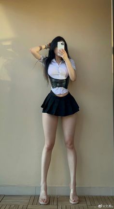 Woman in a white shirt, black corset, and mini skirt posing indoors