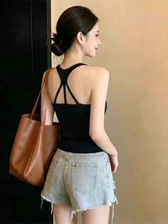 Woman in a black top and denim shorts with a brown bag over her shoulder