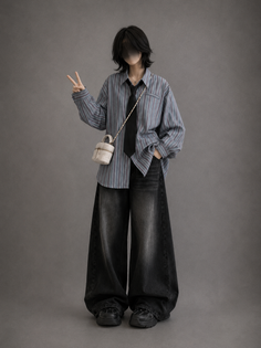 Person with short hair wearing a striped shirt, wide leg jeans, and a black tie