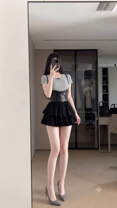 Woman in a black tiered skirt and corset top taking a mirror selfie