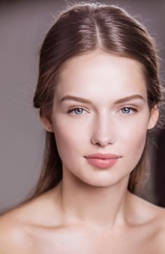 Woman with long brown hair and blue eyes, bare shoulders, looking directly at the camera
