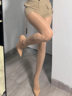 Person wearing high heels, pantyhose, and shorts posing indoors