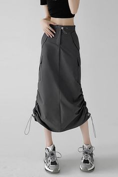 Person wearing a black crop top and a dark grey cargo skirt with sneakers