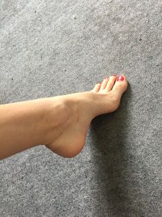 Bare foot with red nail polish on a grey carpet