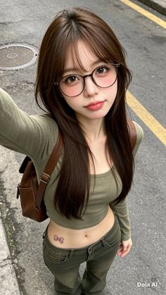 Woman with long hair and glasses wearing a crop top and jeans outdoors
