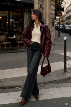 Woman in a burgundy leather jacket and wide leg jeans on a city street