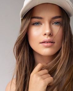 Woman with long brown hair and blue eyes wearing a white hat