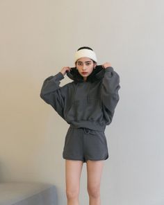 Woman in a dark gray hoodie and shorts with a white headband indoors