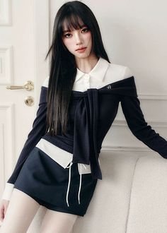Woman with long black hair wearing an off-shoulder top and mini skirt indoors