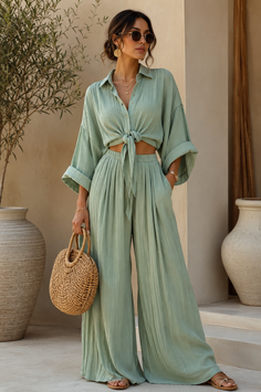 Woman in a light green two-piece outfit with a straw bag and sunglasses outdoors