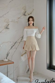 Woman in an off-shoulder top and mini skirt posing indoors