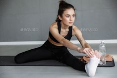 Woman in black athletic wear stretching on a yoga mat indoors