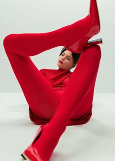 Woman in a red outfit and red boots posing provocatively in a studio