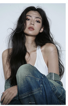 Woman with long dark hair and freckles wearing a white top and denim jacket