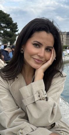 Woman with long dark hair wearing a trench coat outdoors