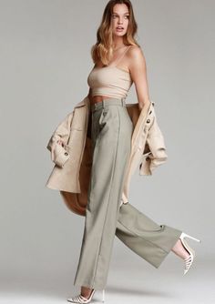 Woman in a crop top, wide leg pants, and a jacket over her shoulders