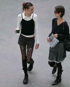 Two women walking outdoors, one with a ponytail and glasses, the other with short hair