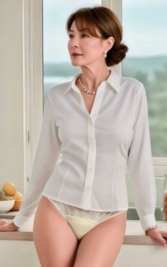 Woman in a white shirt and lace underwear leaning on a kitchen counter