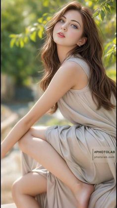 Woman with long wavy hair and a light gray dress posing outdoors