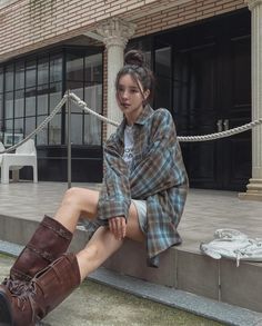 Woman in a plaid shirt and brown boots sitting outdoors