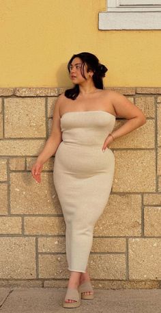 Woman in a strapless dress posing against a stone wall outdoors
