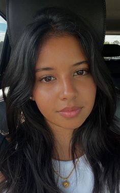 Woman with long black hair wearing earrings and a necklace in a car
