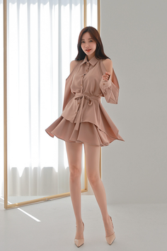 Woman in a short beige dress and high heels posing indoors