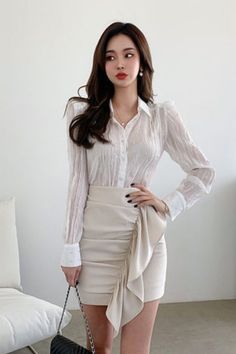 Woman in a white blouse and a beige ruffle mini skirt indoors