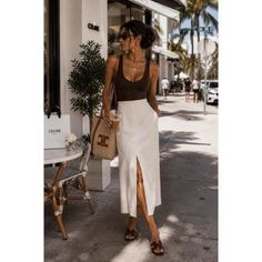 Woman in a white skirt and brown top walking on a sunny street
