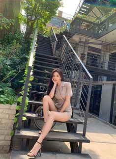 Woman in a short suit and high heels sitting on outdoor stairs