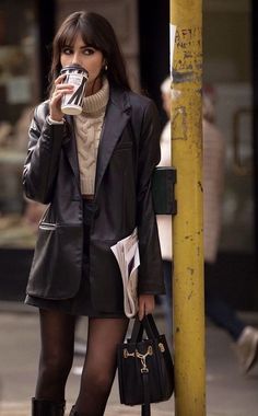 Woman in a leather jacket and mini skirt drinking coffee on a street